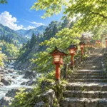 川沿いの石段に赤い灯籠が並ぶ山あいの神社の参道